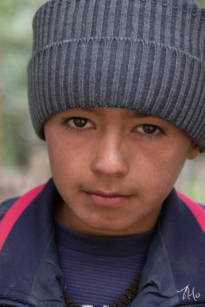 A young boy wearing a beanie and hat.