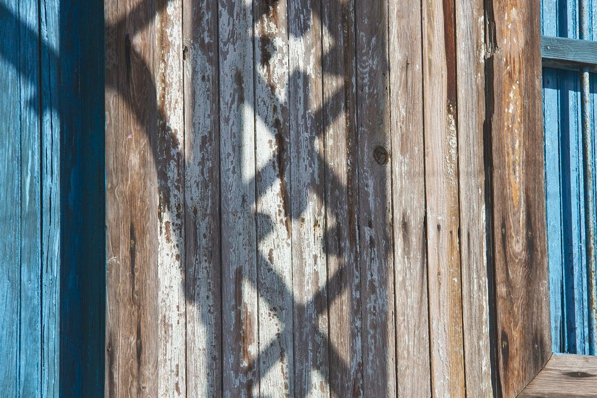 The shadow of a wooden window on a blue wall.