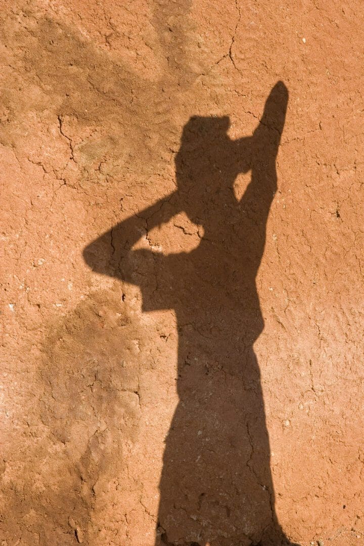 A person's shadow is cast on a dirt wall.