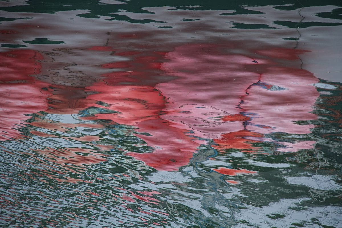 Red balloons reflected in the water.