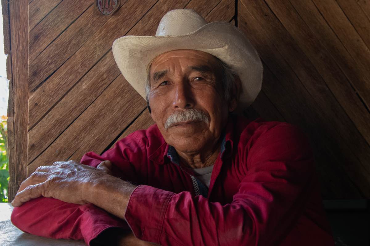 An old man in purple shirt wearing a cowboy hat