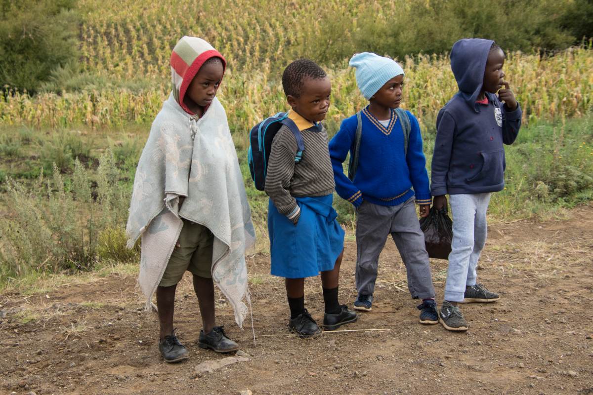 A group of children standing on a dirt road.
