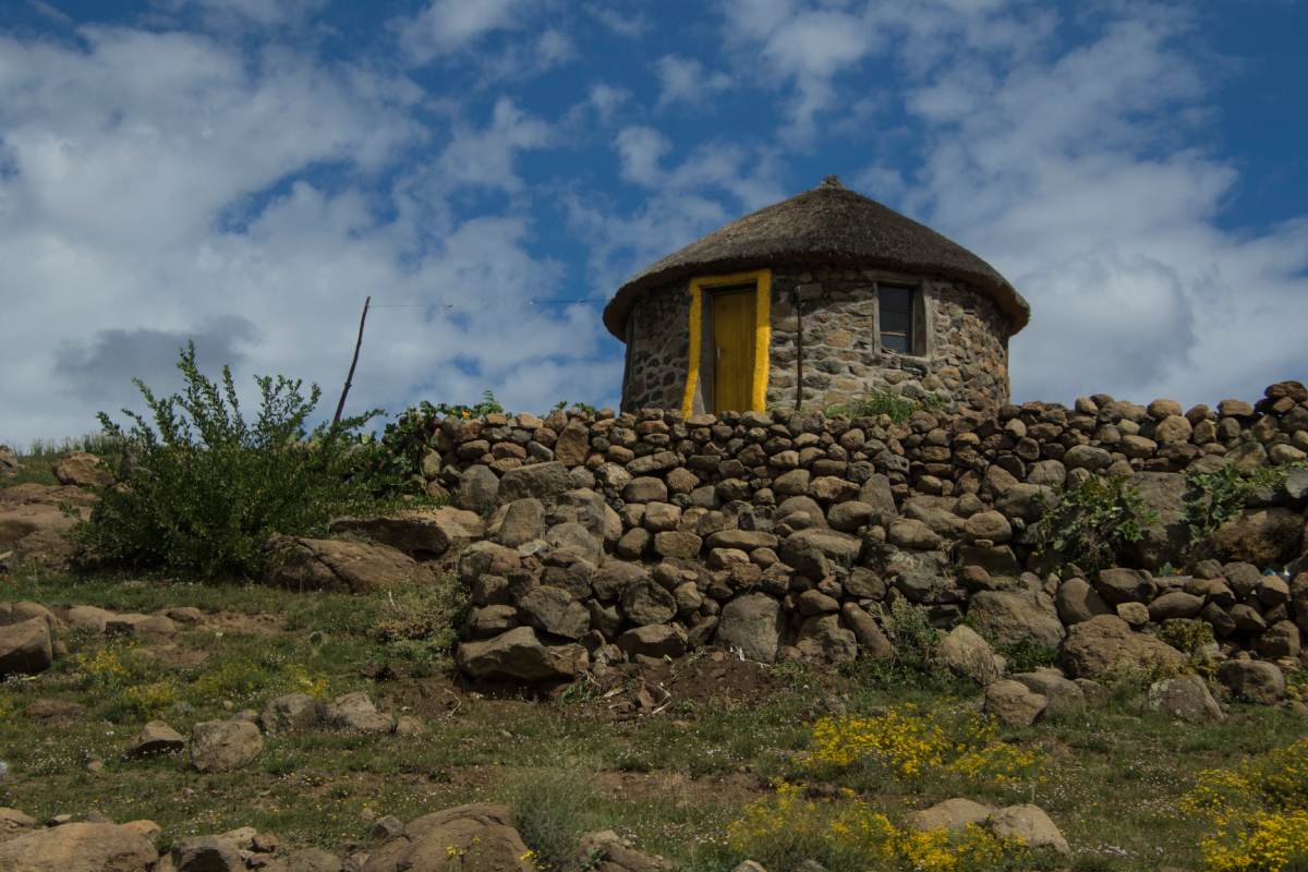 A hut with a yellow door on top of a rocky hill.