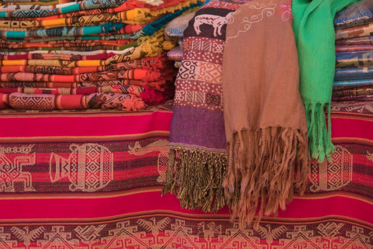 Colorful blankets and scarves are on display at a market.