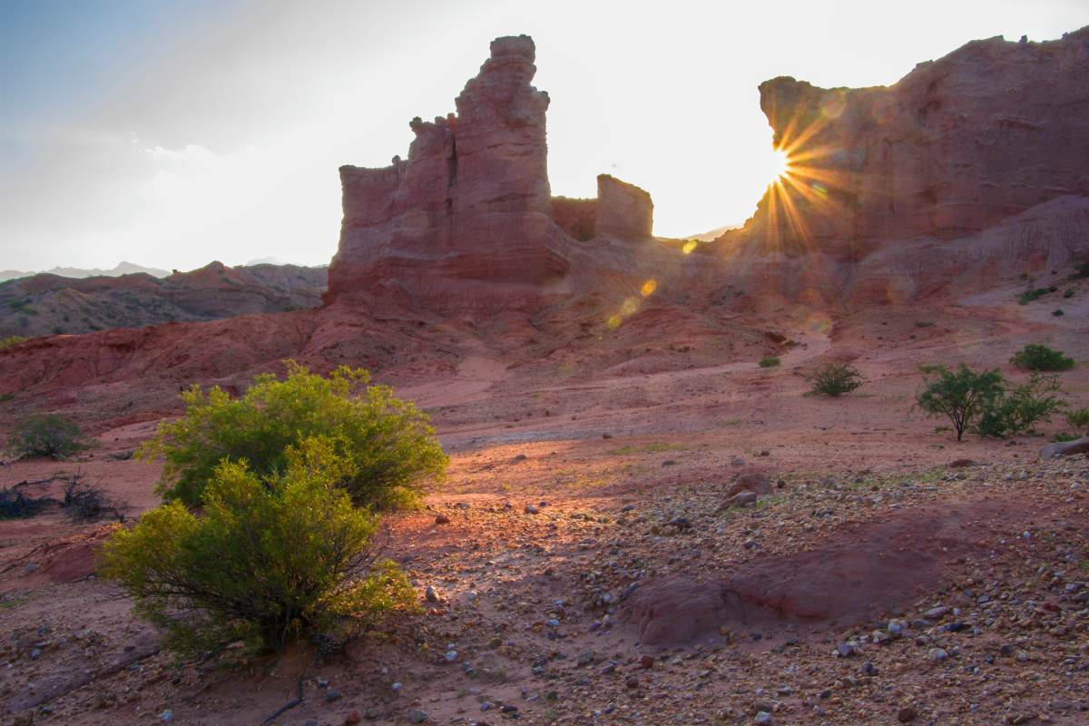 The sun is shining on a red rock formation.