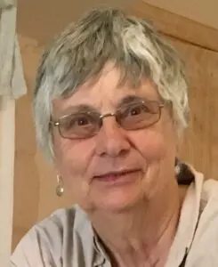 An older woman wearing glasses and a white shirt.