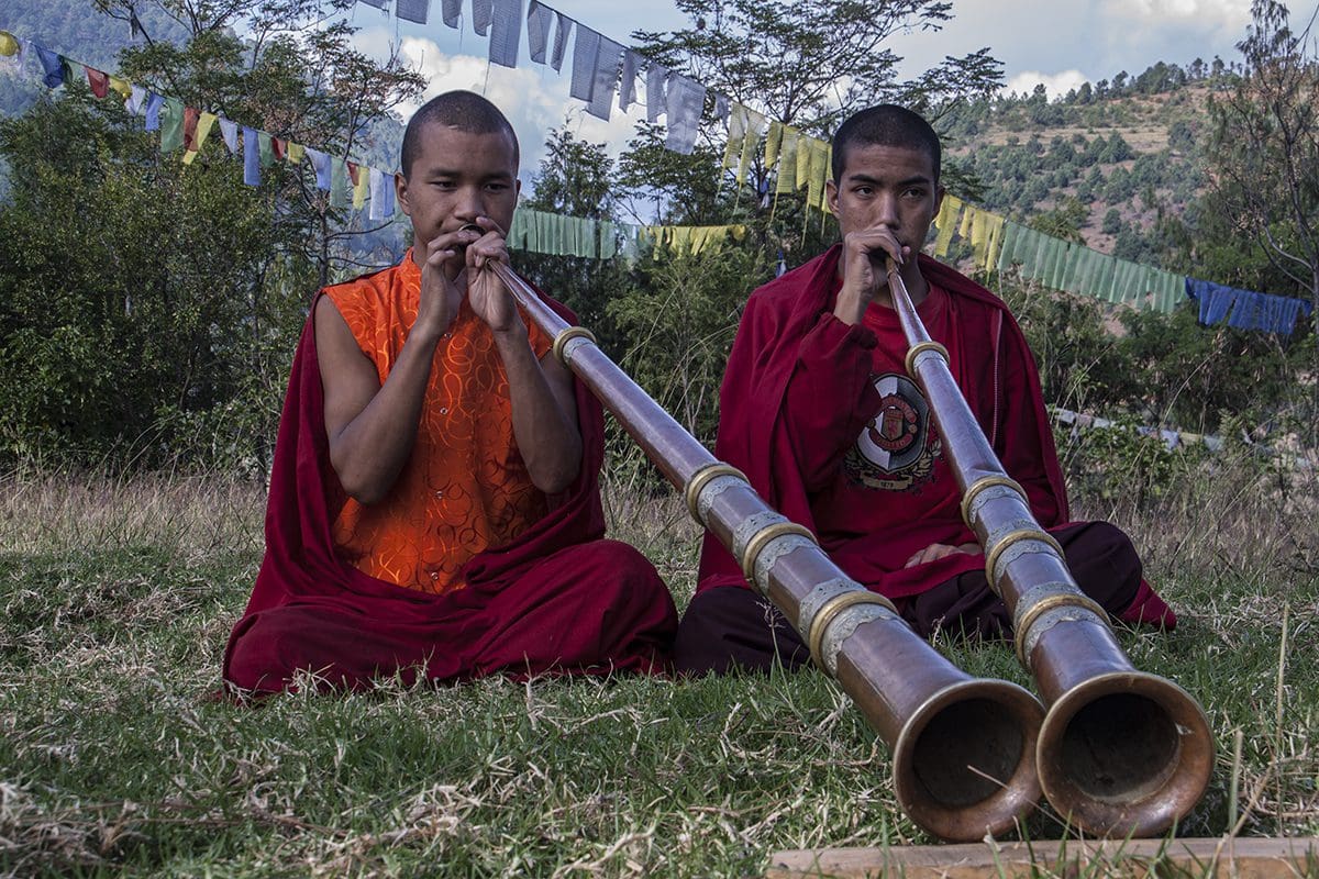 Two buddhist monks playing a bamboo flute.