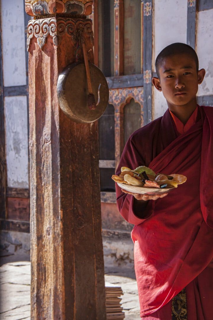 A monk holding a plate of food.