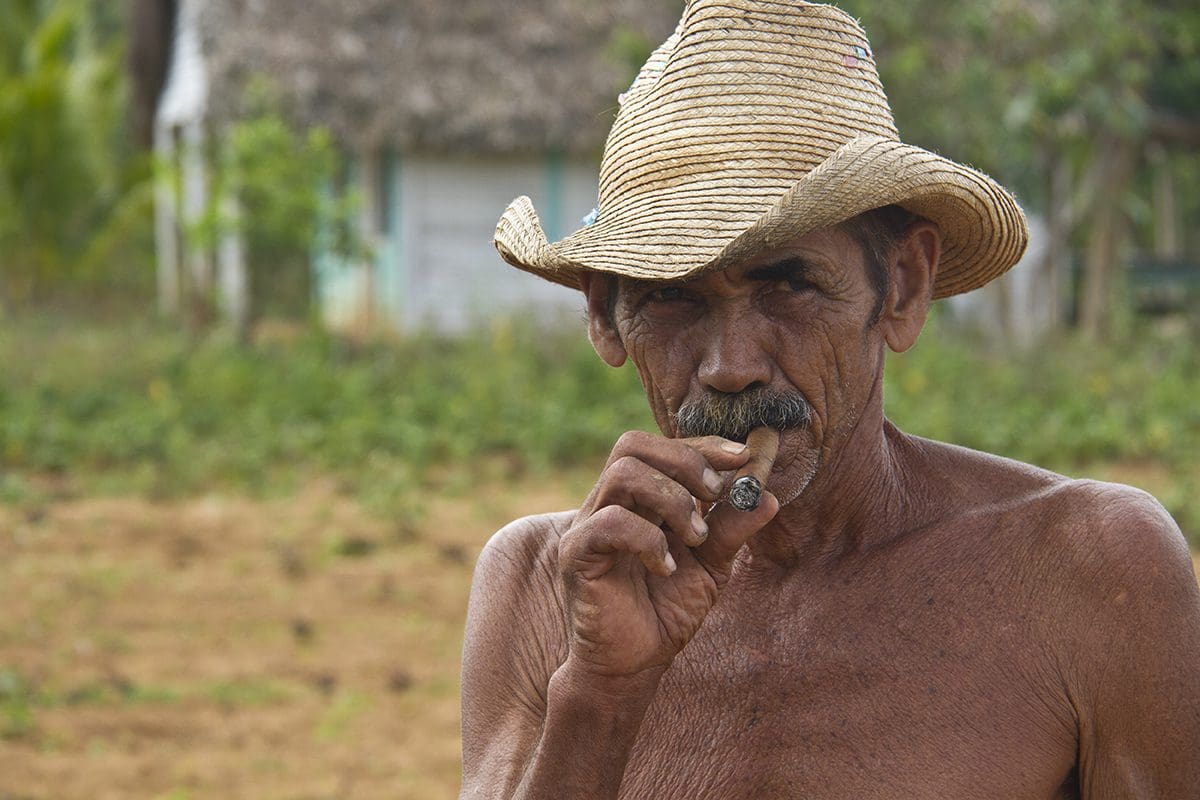 A man in a straw hat smoking a cigarette.