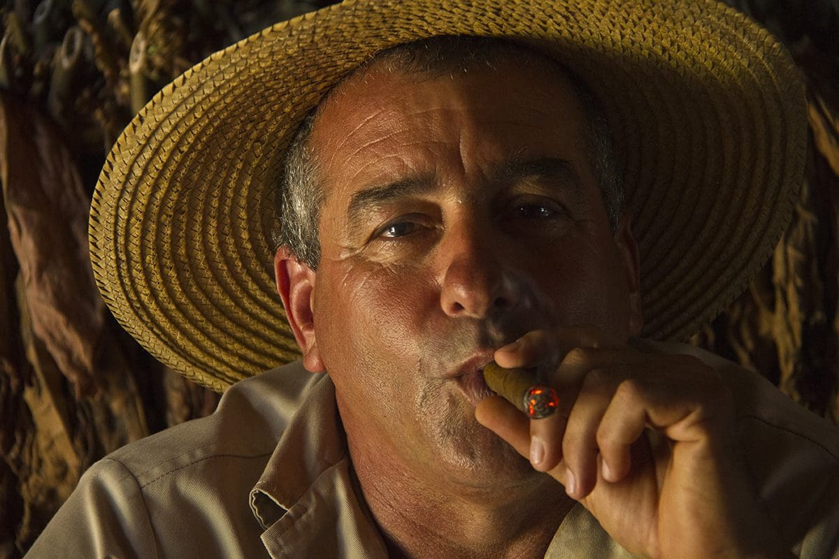 A man in a straw hat smoking a cigar.