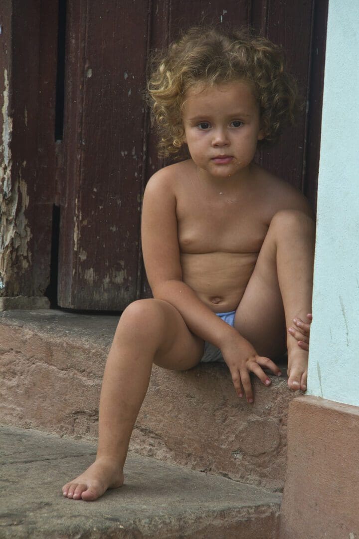 A little girl sitting on the steps of a building.