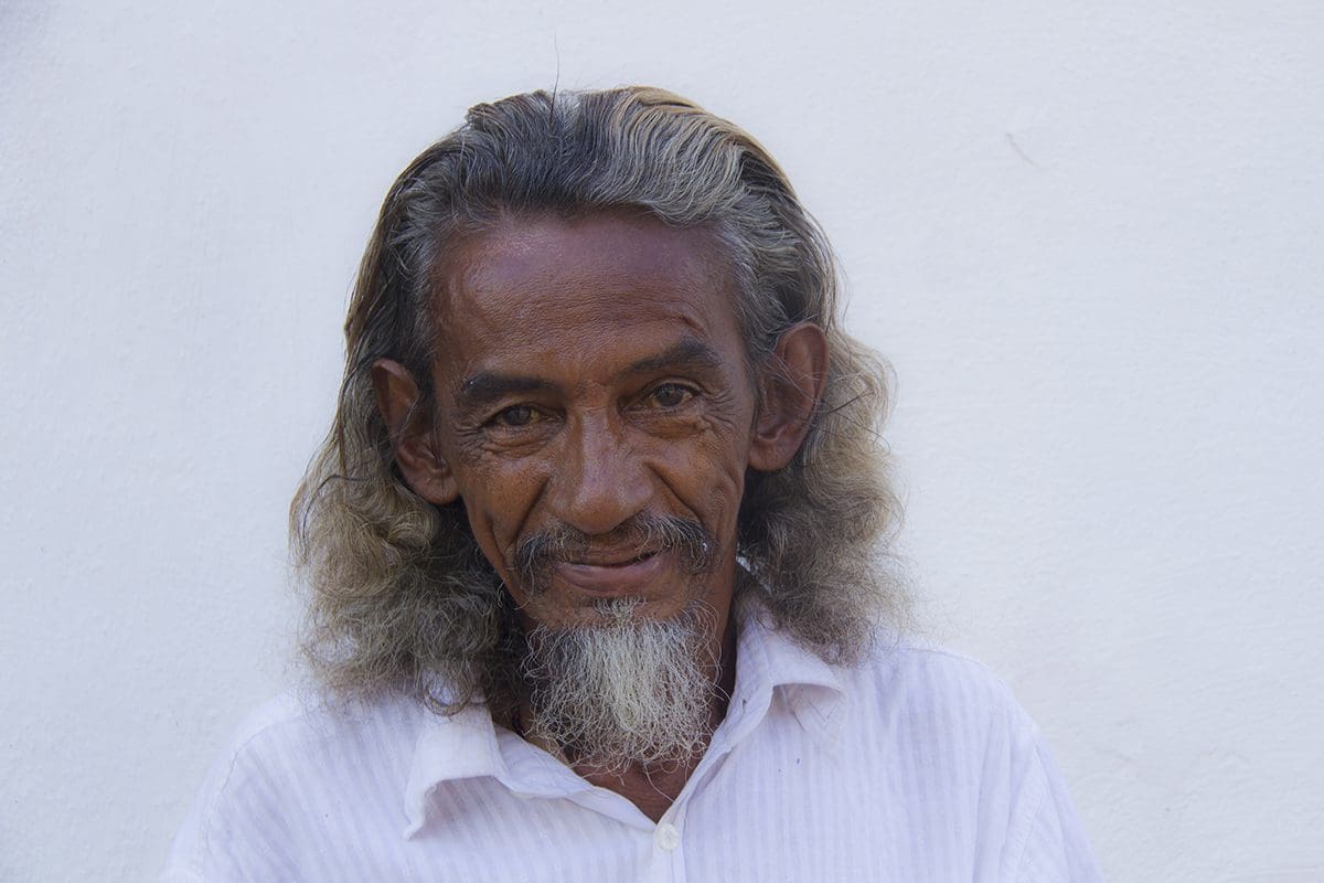 A man with long hair and a white shirt.