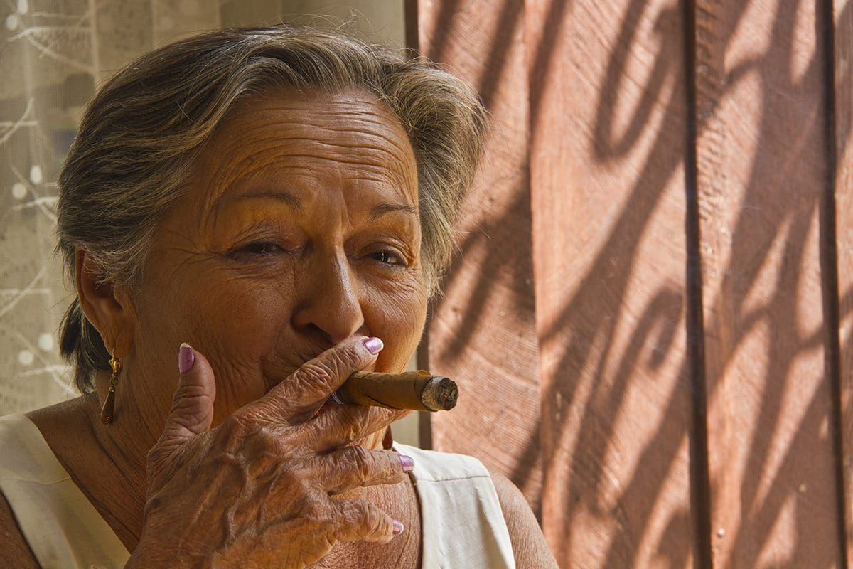 An older woman smoking a cigar.