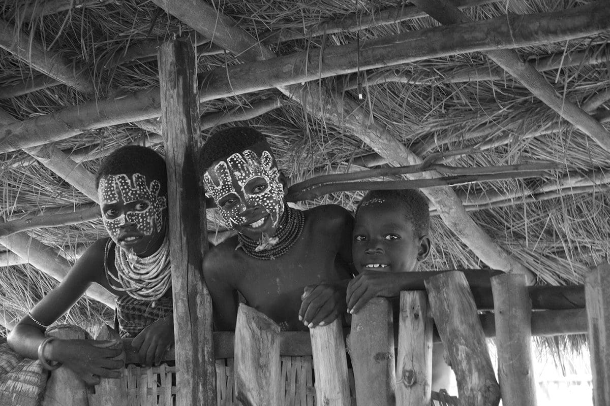 A group of boys in a hut with paint on their faces.