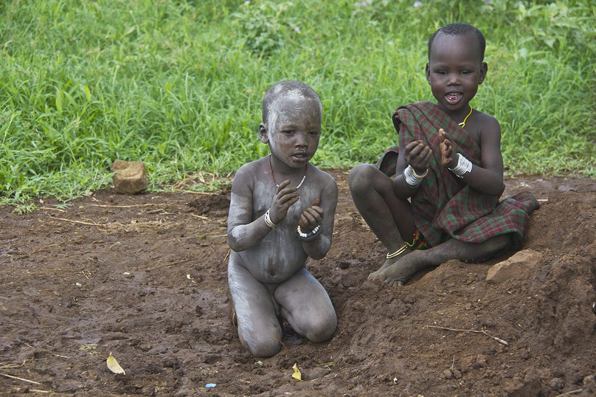 Two children playing in the dirt.