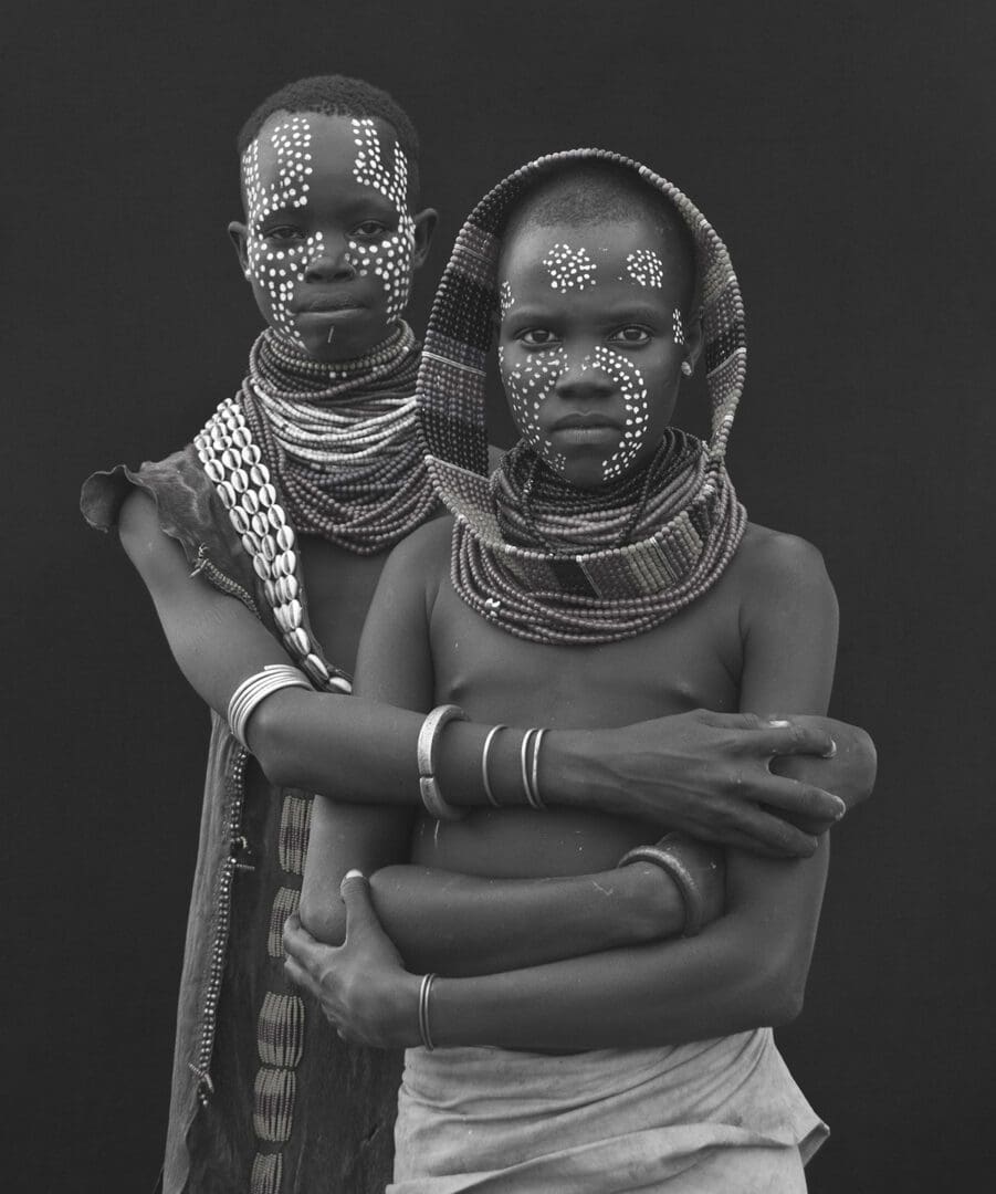 A black and white photo of two people with painted faces.