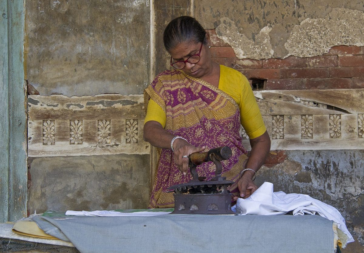 A woman is ironing a piece of cloth on a table.