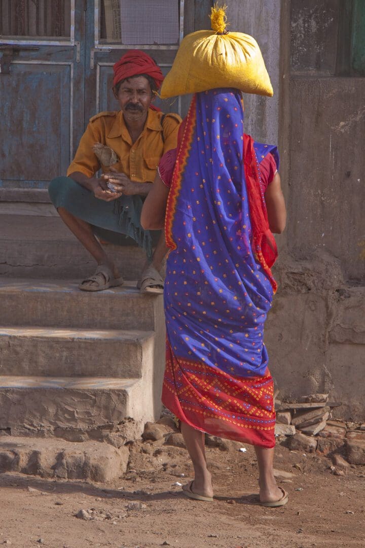 A woman wearing a sari and carrying a hat.