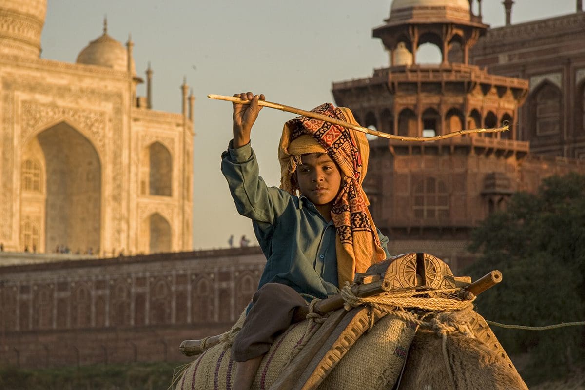 A man riding a camel in front of the taj mahal.