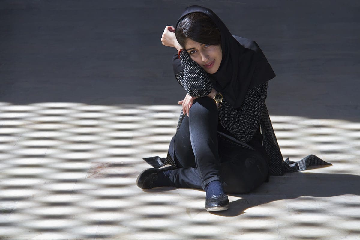 A woman in a hijab sitting on the ground.