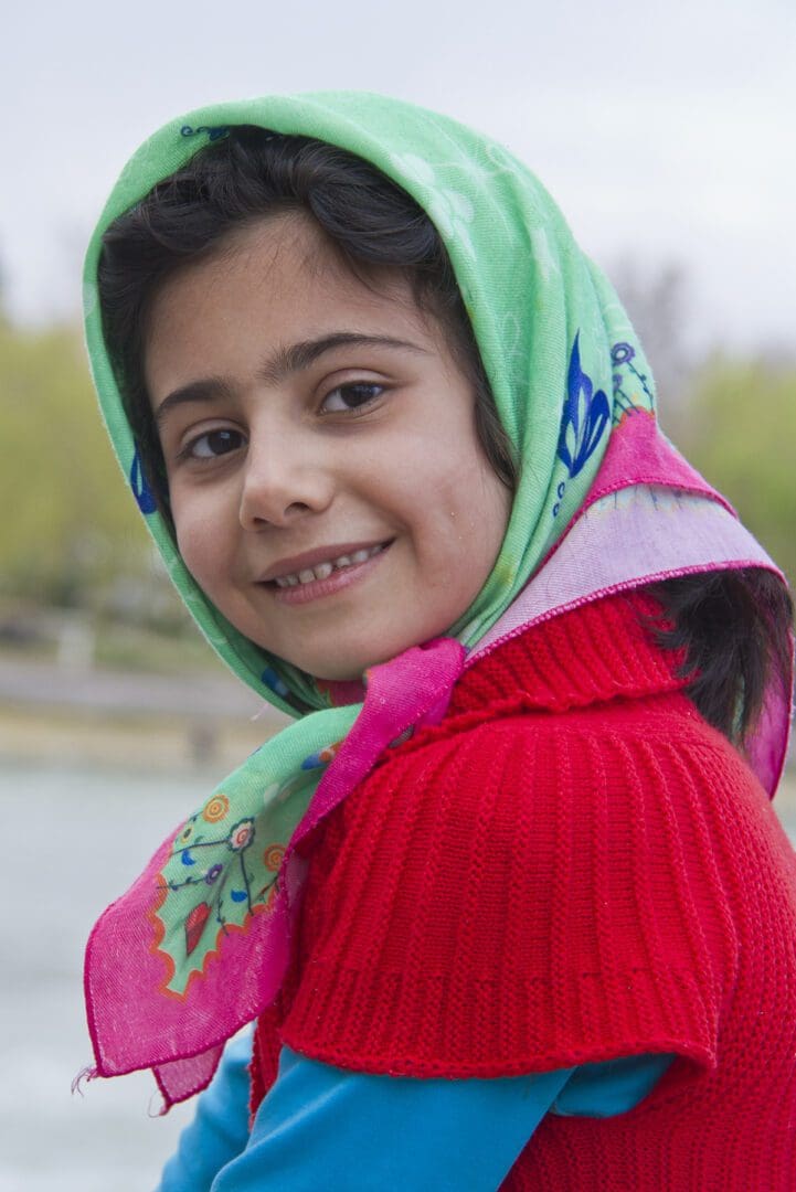 A young girl wearing a scarf and smiling.