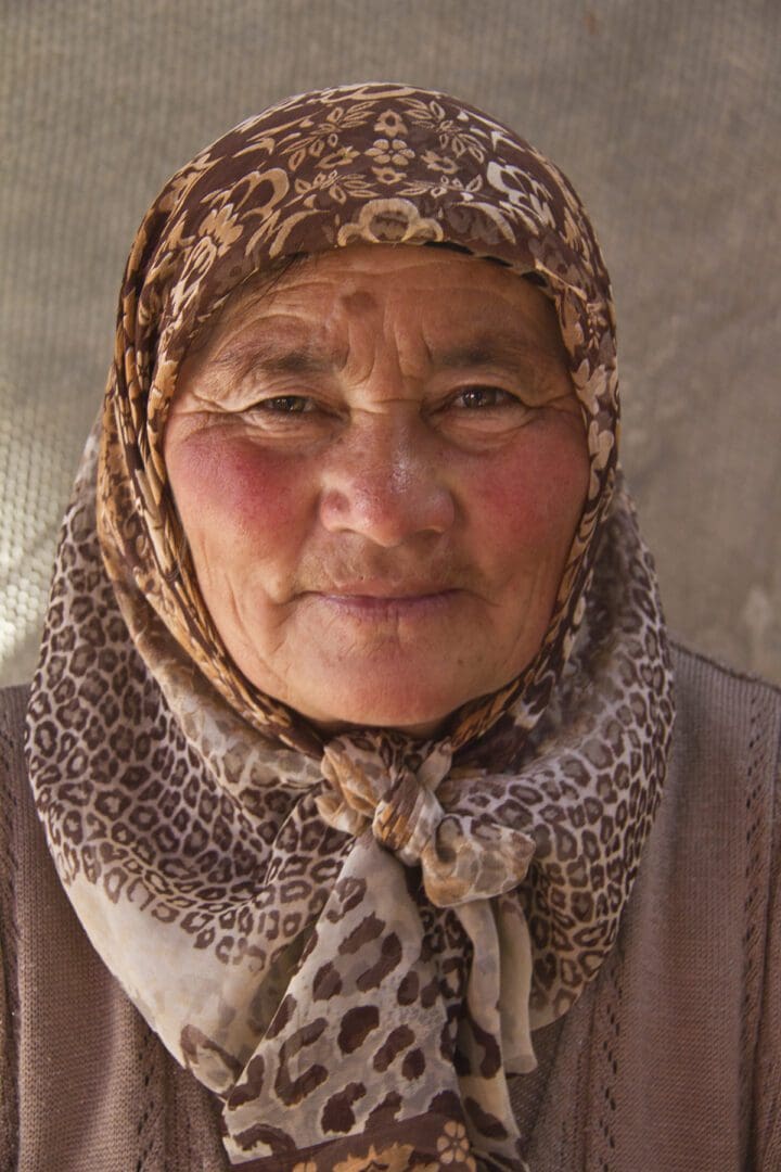 An old woman wearing a scarf and hat.