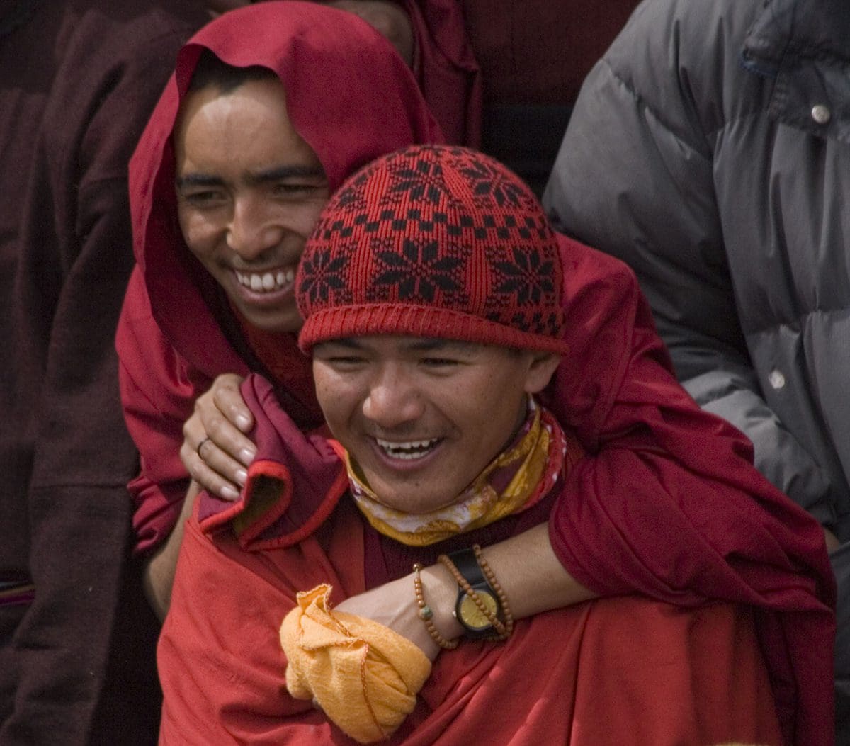 Two buddhist monks hugging in a crowd.