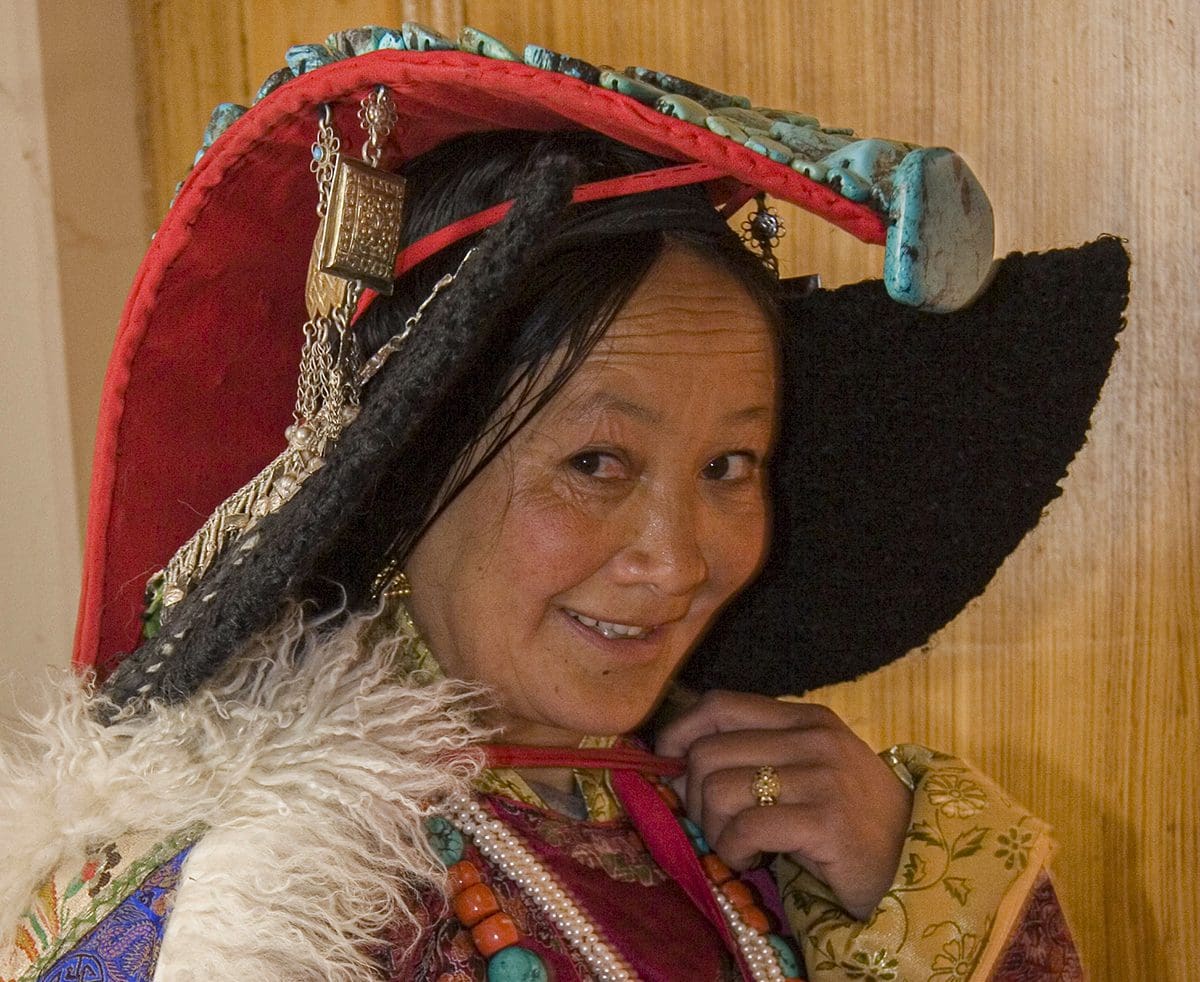 A woman in traditional tibetan clothing is posing for a photo.