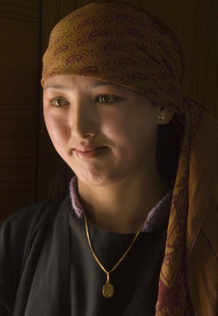 A young girl wearing a scarf and a necklace.