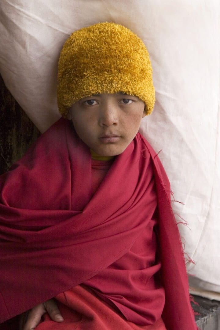 A young monk wearing a red hat.
