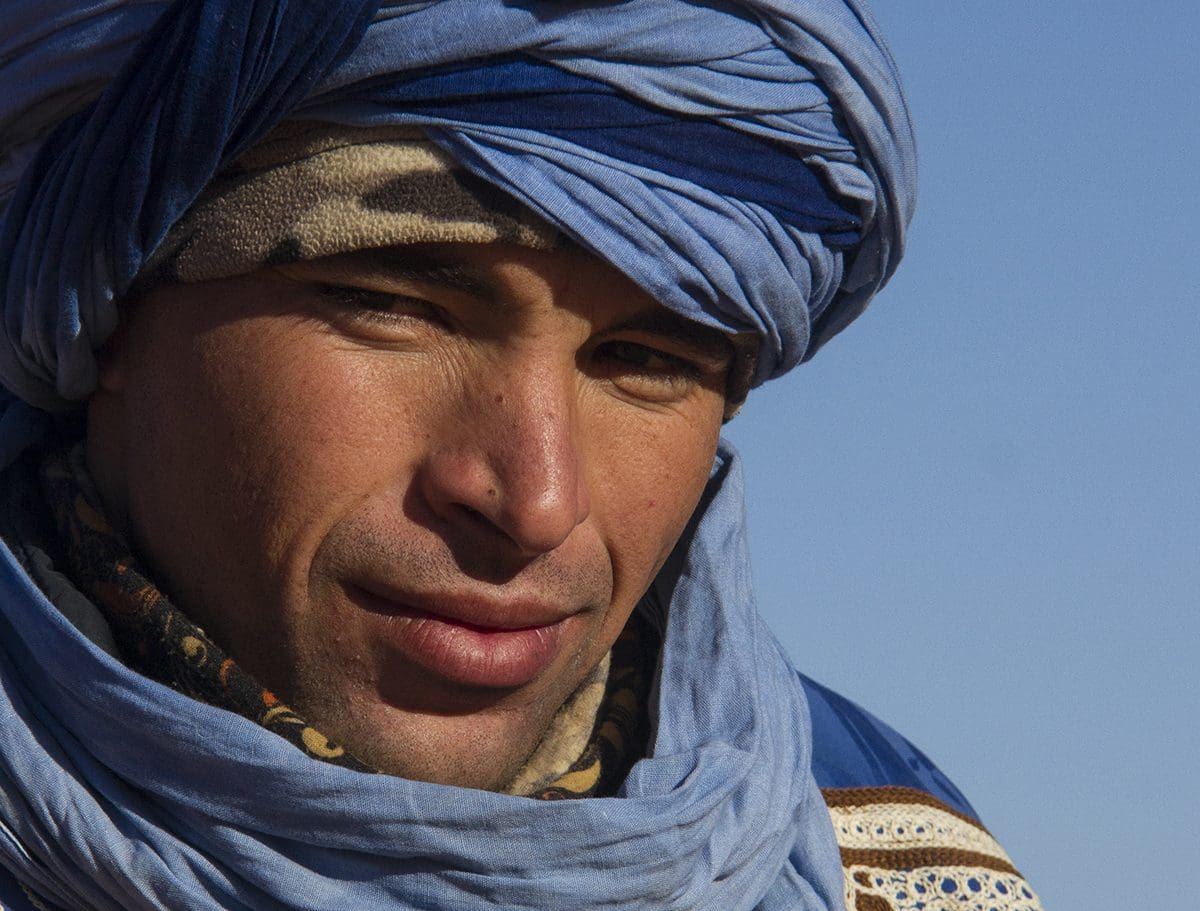 A man in a blue turban is looking at the camera.