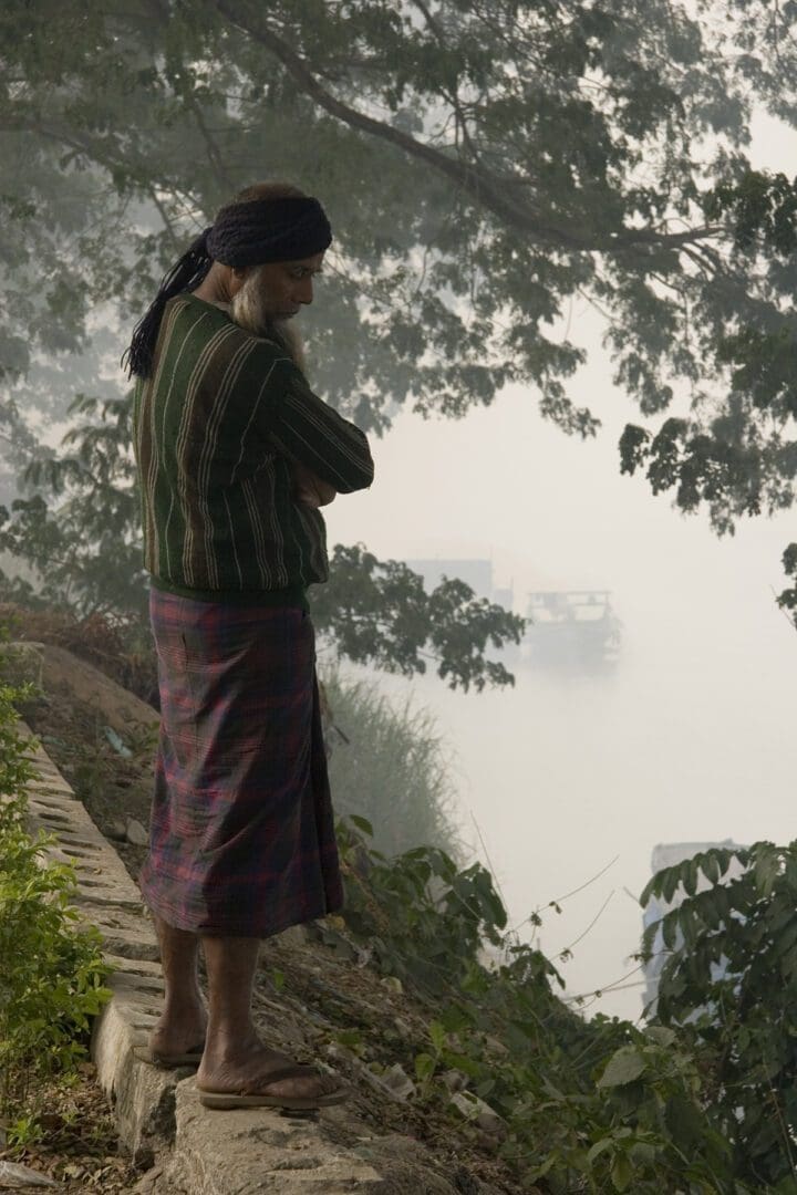 A man standing on a ledge looking at water.