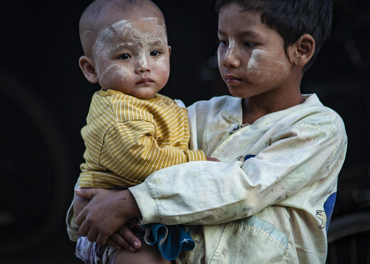 A boy holding a child with a white face.