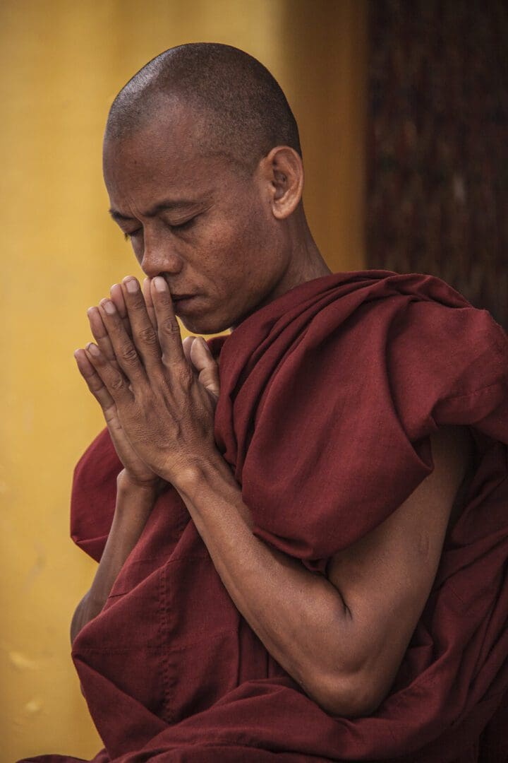 A monk in a red robe is praying.