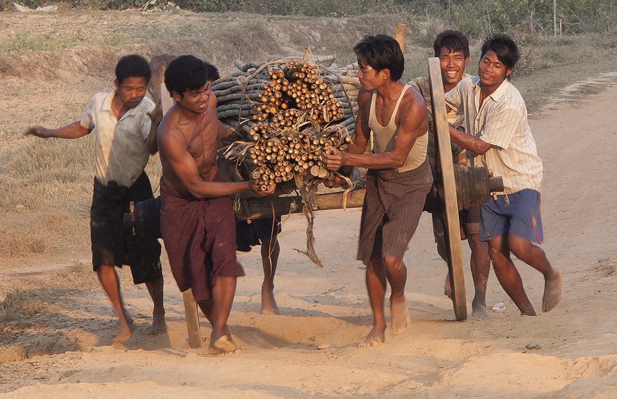 A group of men carrying logs on a cart.