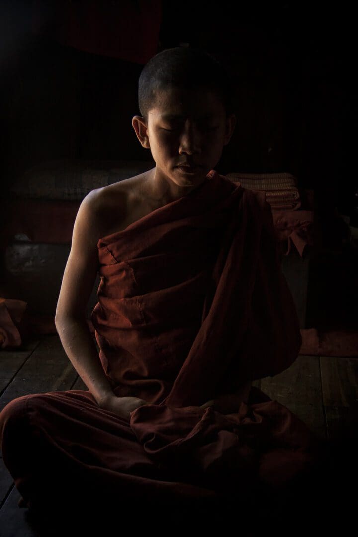 A buddhist monk sitting in a dark room.