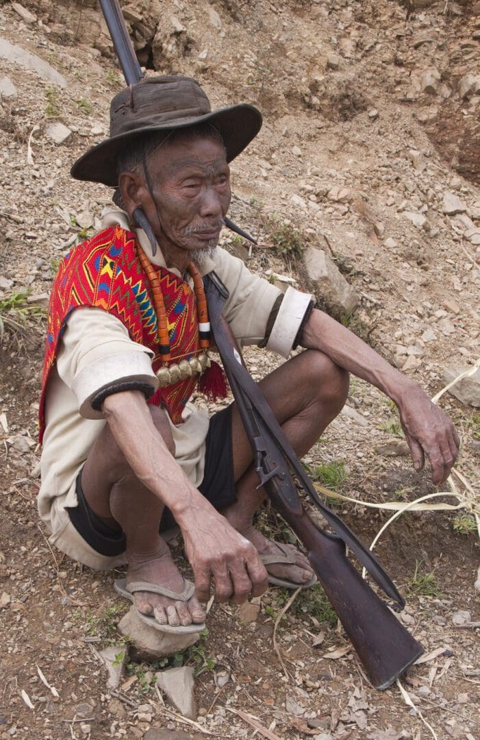 A man sitting on the ground with a rifle.