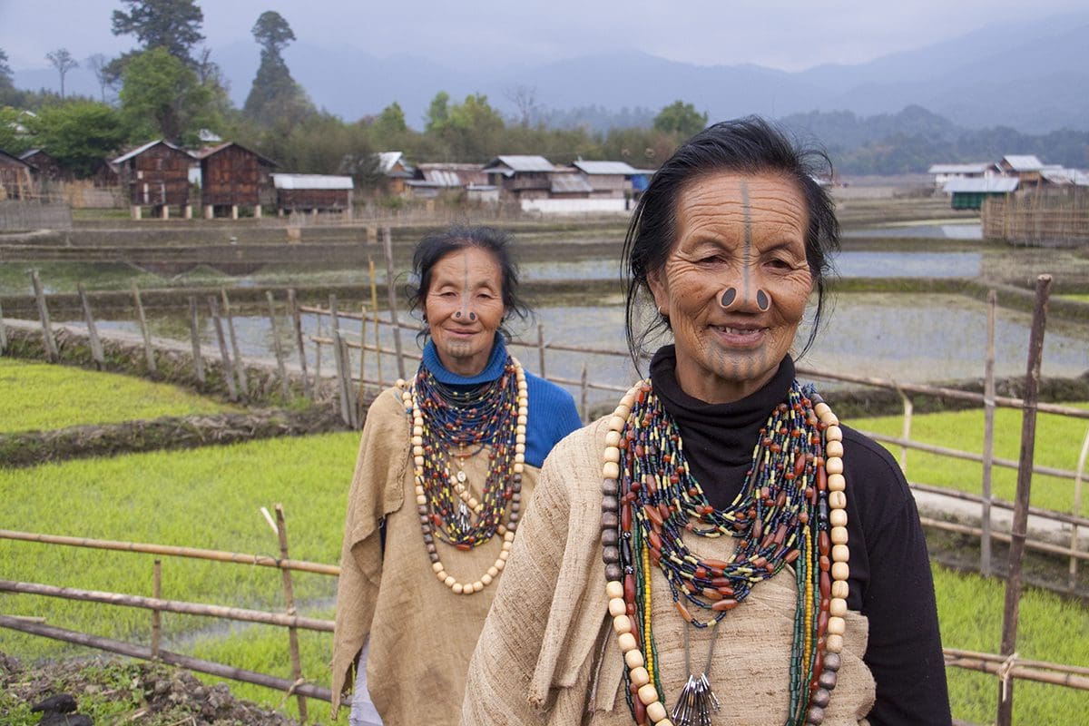 Two women standing in front of a rice field.