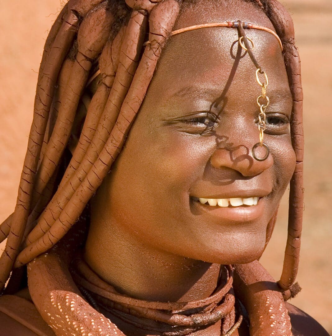 A woman with dreadlocks smiling in the desert.