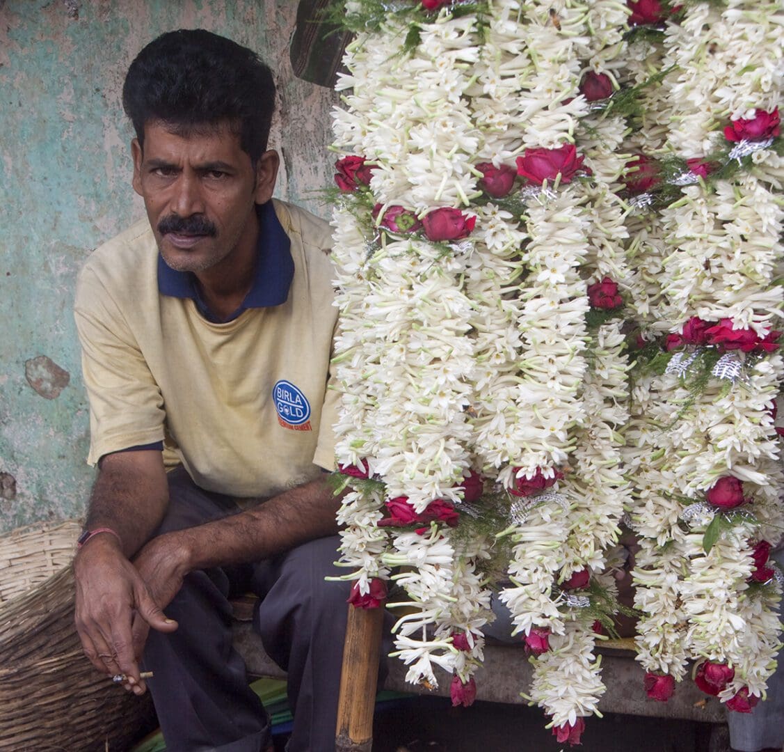 A man sitting in front of a display of flowers.