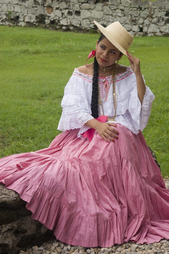 A woman in a pink dress sitting on a rock.