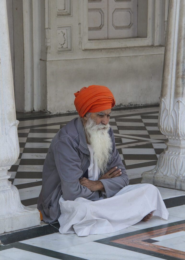 An indian man sitting on the floor.