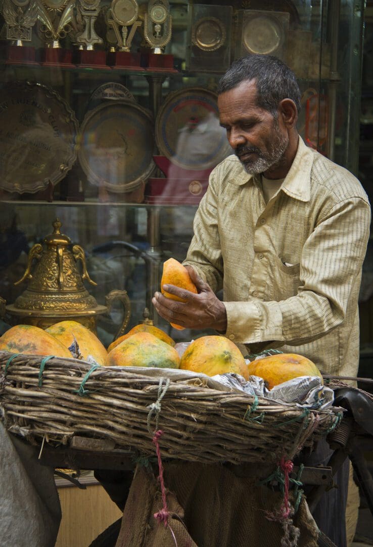 A man with a basket of mangoes.