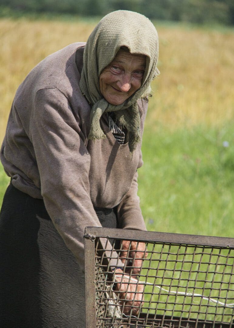 An old woman in a field with a basket.