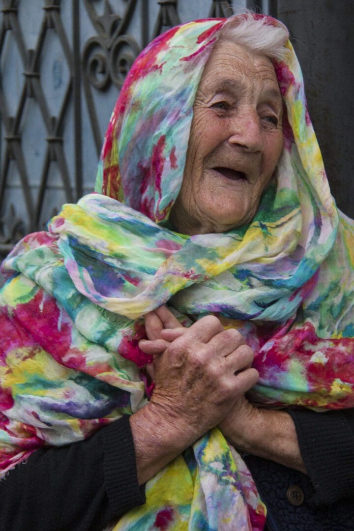 An old woman wearing a colorful scarf.