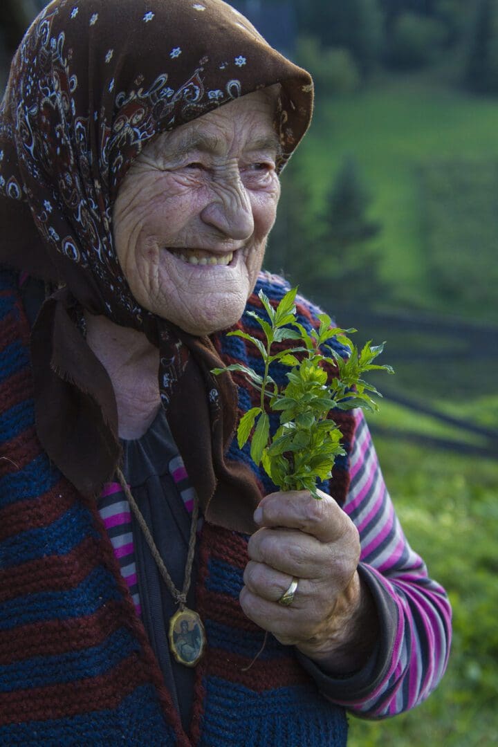 An old woman holding a plant.