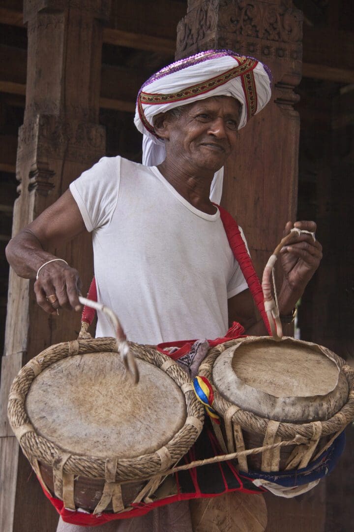 A man in a turban playing drums.