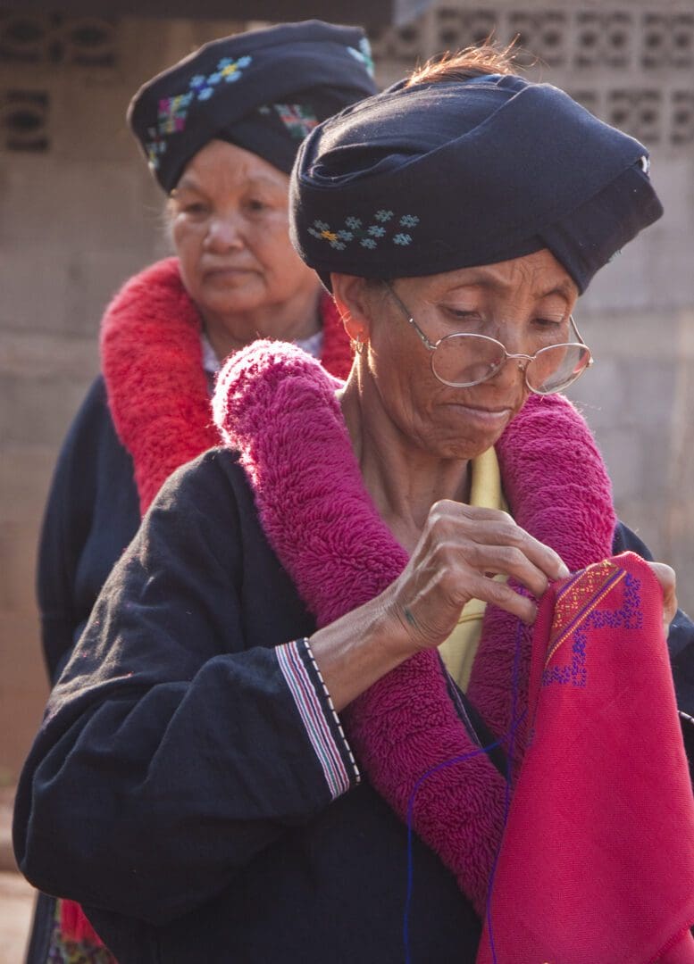 Two women are working on a piece of cloth.