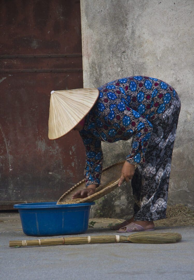 A woman in a hat is pouring water into a bucket.