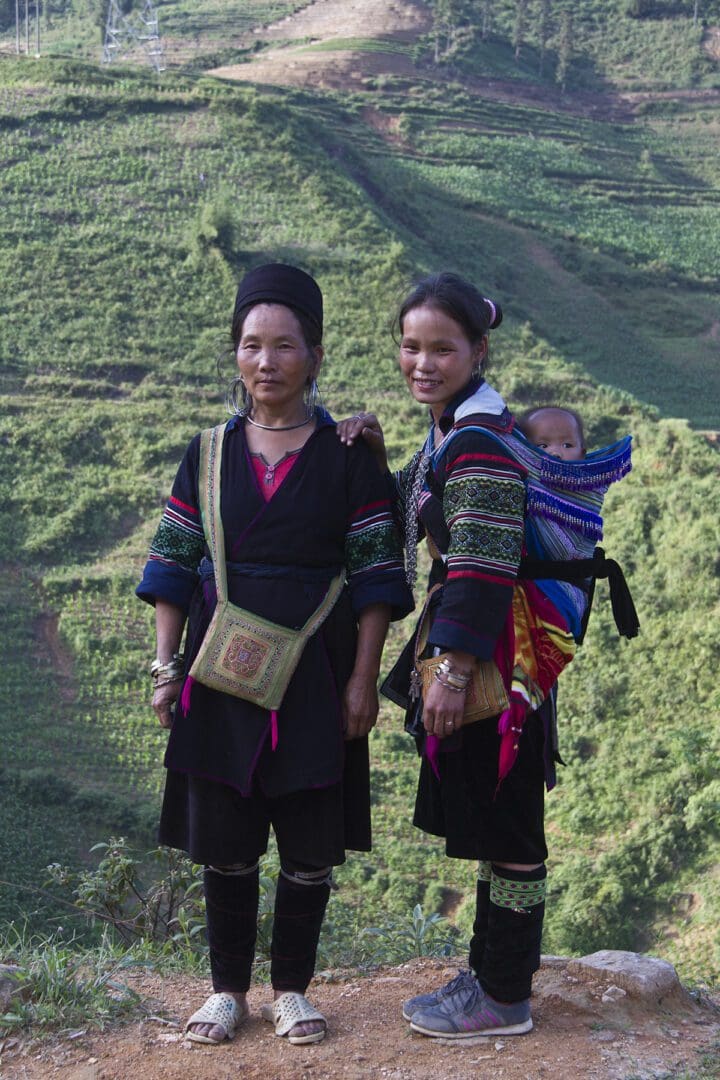 Two women in traditional clothing standing on a hillside.